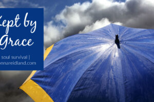 Big blue and yellow umbrella against a dark blue cloudy sky with text that reads, Kept by Grace