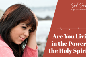 Depressed and discouraged woman with auburn hair sitting by the shore with text that reads, Are You Living in the Power of the Holy Spirit?