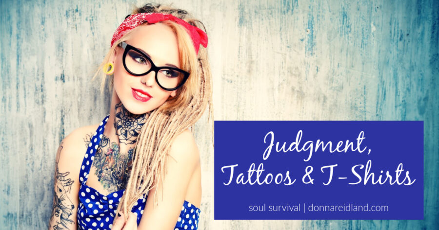 Young woman with tattoos and a red bandanna with text that reads, Judgment, Tattoos & T-Shirts.