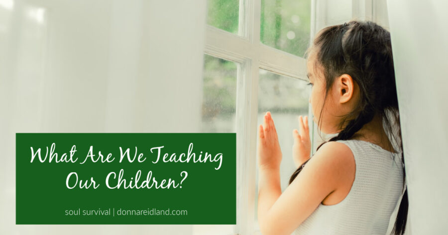 Little girl looking sadly out the window with text that reads, What Are We Teaching Our Children?