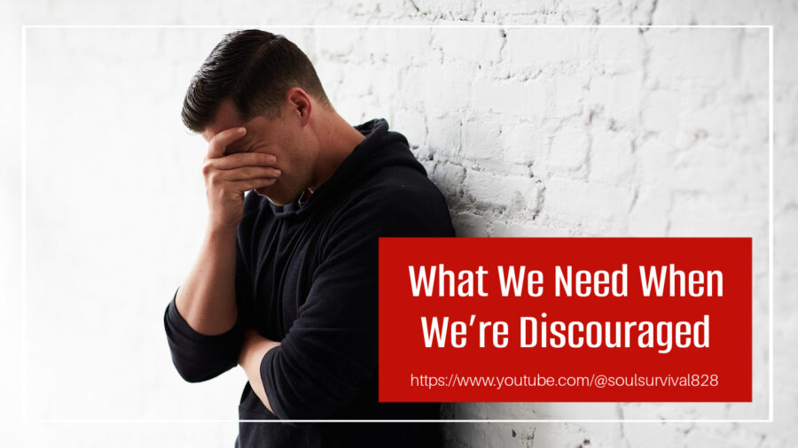 Discouraged man leaning against a wall with his hand over his face with text that reads, What We Need When We're Discouraged